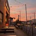 Terraza al aire libre con mesas y luces decorativas durante el atardecer