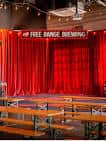 Escenario interior con cortinas rojas y mesas para eventos