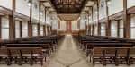 Interior del salón de la iglesia con bancos y techo de vigas expuestas