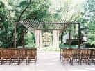 Área de ceremonia al aire libre con bancas y pérgola en el jardín