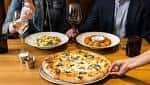 Mesa con pizza y platos de pasta en ambiente acogedor