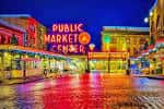 Pike Place Market iluminado por la noche con reflejos en el suelo mojado