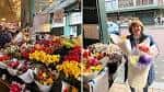 Interior del mercado con puestos de flores coloridas y una persona sosteniendo un ramo