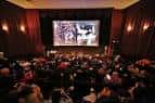 Interior del auditorio principal con pantalla de cine y público sentado