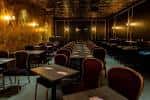 Interior del local Mic Drop Comedy con mesas y butacas rojas