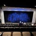 Interior del auditorio de Stageworks Theatre con escenario y cortina azul