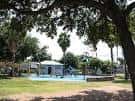 Área recreativa con piscina infantil y sombra de árboles en el parque