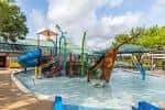 Área de juegos acuáticos infantiles con toboganes y estructuras coloridas en el Quillian Center