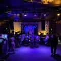 Interior del teatro con público y banda en escena bajo luces azules
