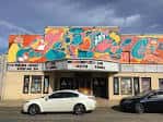 Fachada exterior del Neighborhood Theatre con mural colorido y letrero de cartelera