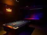 Interior del The Banshee Bar con mesa de billar y escenario iluminado