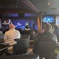 Concierto en vivo con banda actuando en el escenario y público sentado
