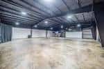 Espacio interior amplio y vacío con techo industrial y piso de concreto pulido