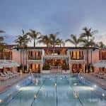 Vista exterior del hotel con piscina y palmeras al atardecer