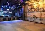 Interior del venue con barra de skiball y decoración industrial iluminada