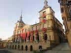 Fachada lateral del Palacio Consistorial de Toledo decorado con banderas rojas al atardecer