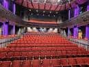 Interior del auditorio con butacas rojas y escenario