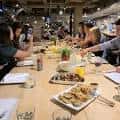 Grupo de personas compartiendo comida en una mesa larga durante un evento social
