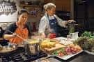 Clase de cocina con dos mujeres preparando alimentos en una cocina moderna