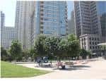 Espacio abierto con árboles y personas descansando bajo edificios altos