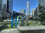 Vista panorámica del Urban Triangle Park con estructuras de juego modernas y rascacielos al fondo