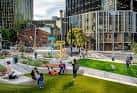 Personas disfrutando del parque en un día soleado, mostrando el diseño urbano y áreas verdes