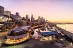Vista panorámica del muelle 66 al atardecer con el skyline de Seattle