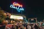 Vista nocturna de la fachada exterior de Gilley's Dallas con su icónico letrero luminoso y multitud en la entrada