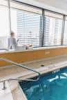 Piscina interior del hotel con vistas a la ciudad y una persona relajándose