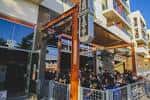 Terraza al aire libre con estructura de madera y personas disfrutando del ambiente