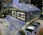 Fachada nocturna de la biblioteca mostrando el diseño geométrico iluminado en la ciudad