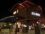 Fachada nocturna del Pacific Beach AleHouse iluminada con luces cálidas