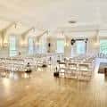 Sala principal del DAR Rainier Chapter House preparada para una ceremonia con sillas blancas y suelo de madera