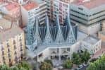 Perspectiva aérea de la iglesia mostrando su diseño único con techos en forma de velas y entorno urbano