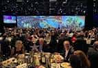 Banquete formal en gran salón con pantalla panorámica al fondo