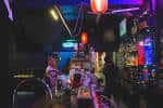 Interior del bar con iluminación de neón y ambiente festivo