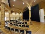 Sala de eventos interior con escenario y disposición en semicírculo
