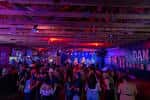 Interior del local Dan Electro's con público asistiendo a un evento musical bajo iluminación de colores