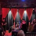 Escenario interior del club con cortinas rojas y ambiente de espectáculo en vivo
