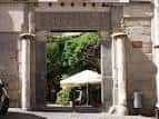 Entrada principal del Salón Rico con arco de piedra y vegetación al fondo