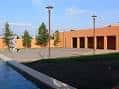 Plaza frontal del centro cultural con árboles y farolas bajo cielo despejado