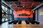 Sala de eventos interior con escenario iluminado en rojo y disposición de asientos