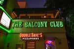 Fachada nocturna del The Balcony Club con letrero de neón verde