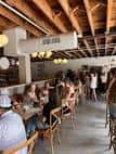 Sala interior con techo de vigas de madera, mesas ocupadas por clientes y ambiente acogedor