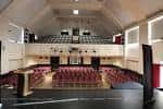 Interior del auditorio con butacas rojas y escenario
