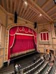 Interior del auditorio con cortinas rojas y butacas clásicas