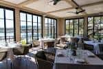 Sala de eventos interior con mesas dispuestas para cena y vista al lago