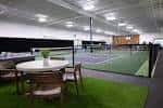 Área de juego con cancha de pickleball y zona de descanso con césped artificial