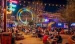 Vista nocturna del Truck Yard en Houston con luces de neón y gente disfrutando al aire libre