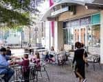 Vista exterior del mercado con mesas al aire libre y personas disfrutando